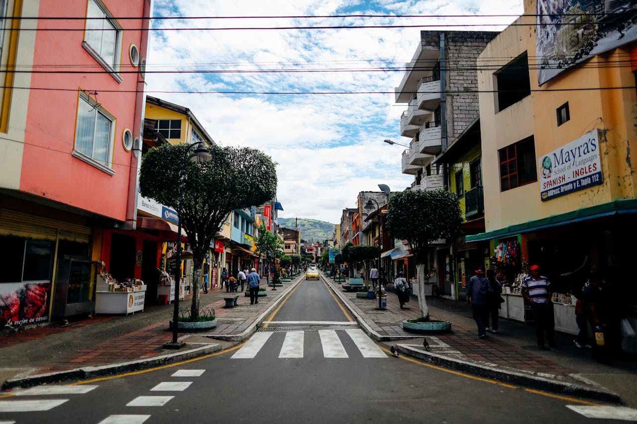 Lively street view in an Ecuadorian town with shops, pedestrians, and urban architecture.